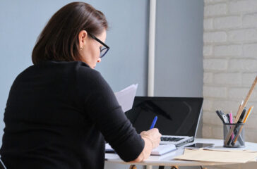 woman-writing-in-notebook-desk-laptop.jpg
