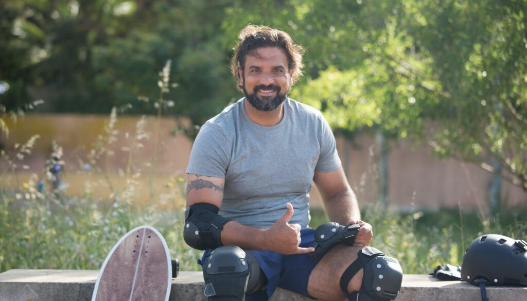 man wearing elbow and knee pads sitting on concrete bench